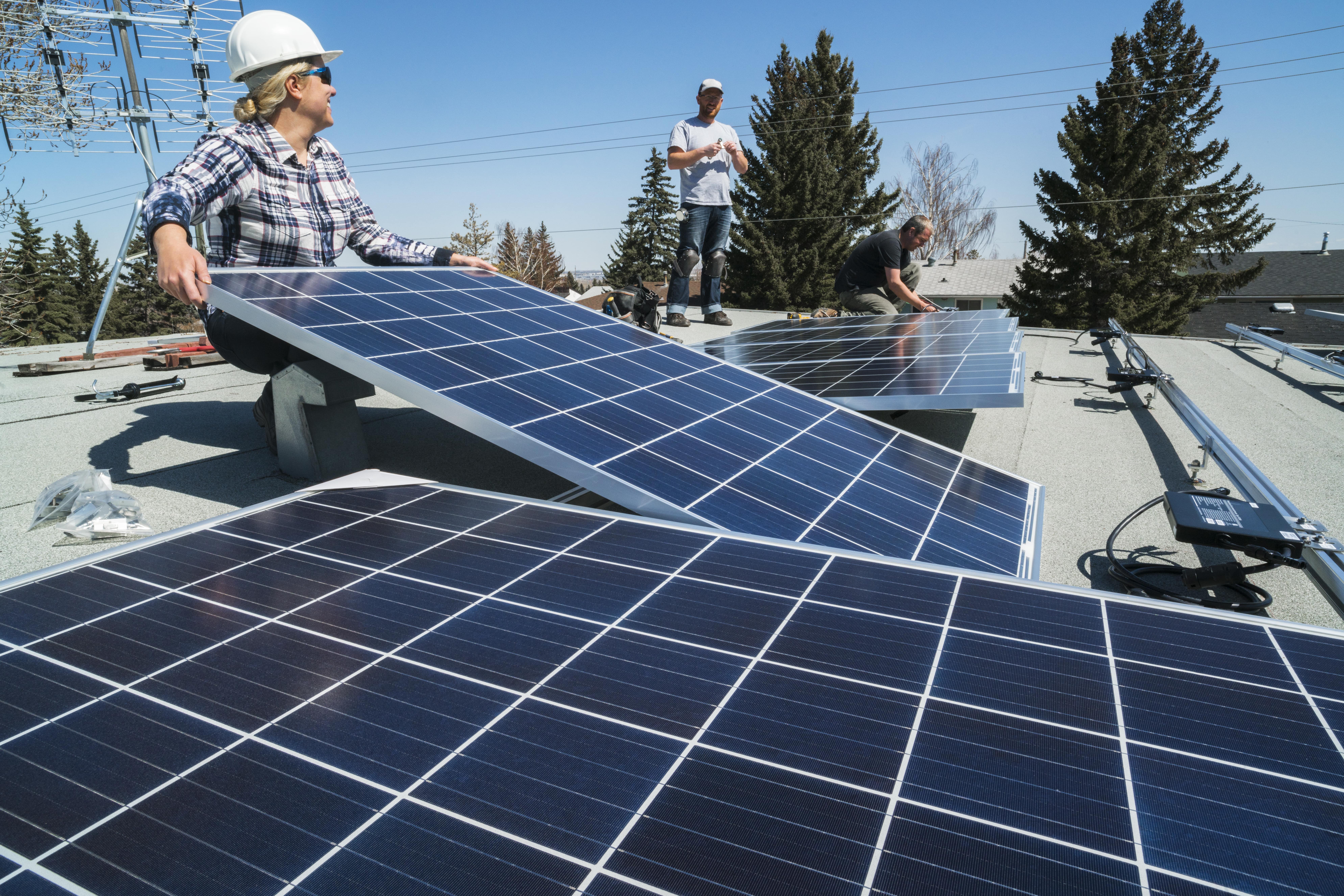 A group of workers installing solar panels on a roof